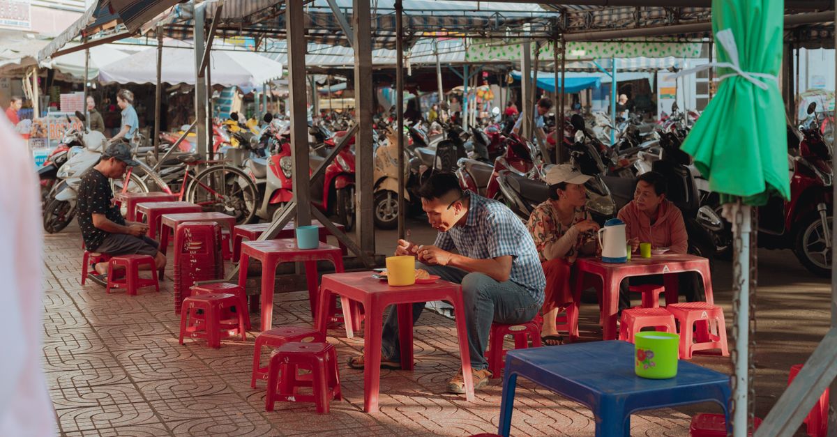 Casual outdoor street dining in a Vietnamese market with plastic stools