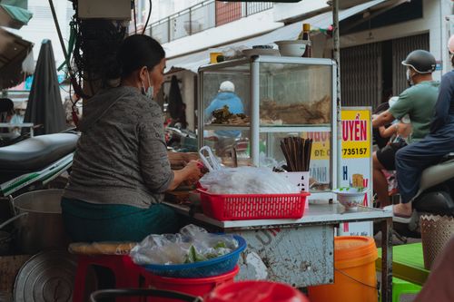 Free Street food vendor preparing dishes in bustling Vietnamese market. Stock Photo
