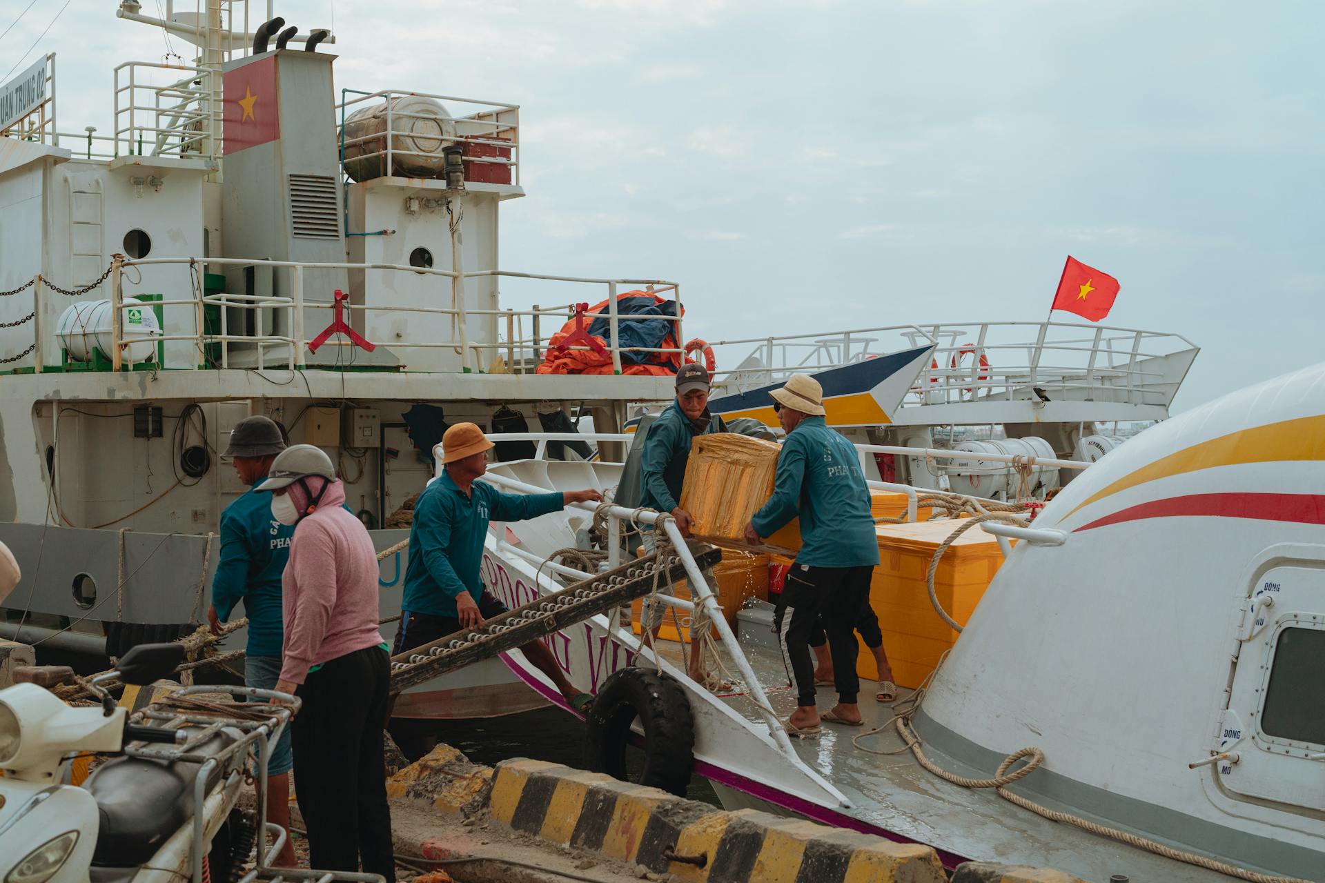 Dock workers unloading cargo at a port in Bình Thuận, Vietnam. Busy maritime scene during daytime.