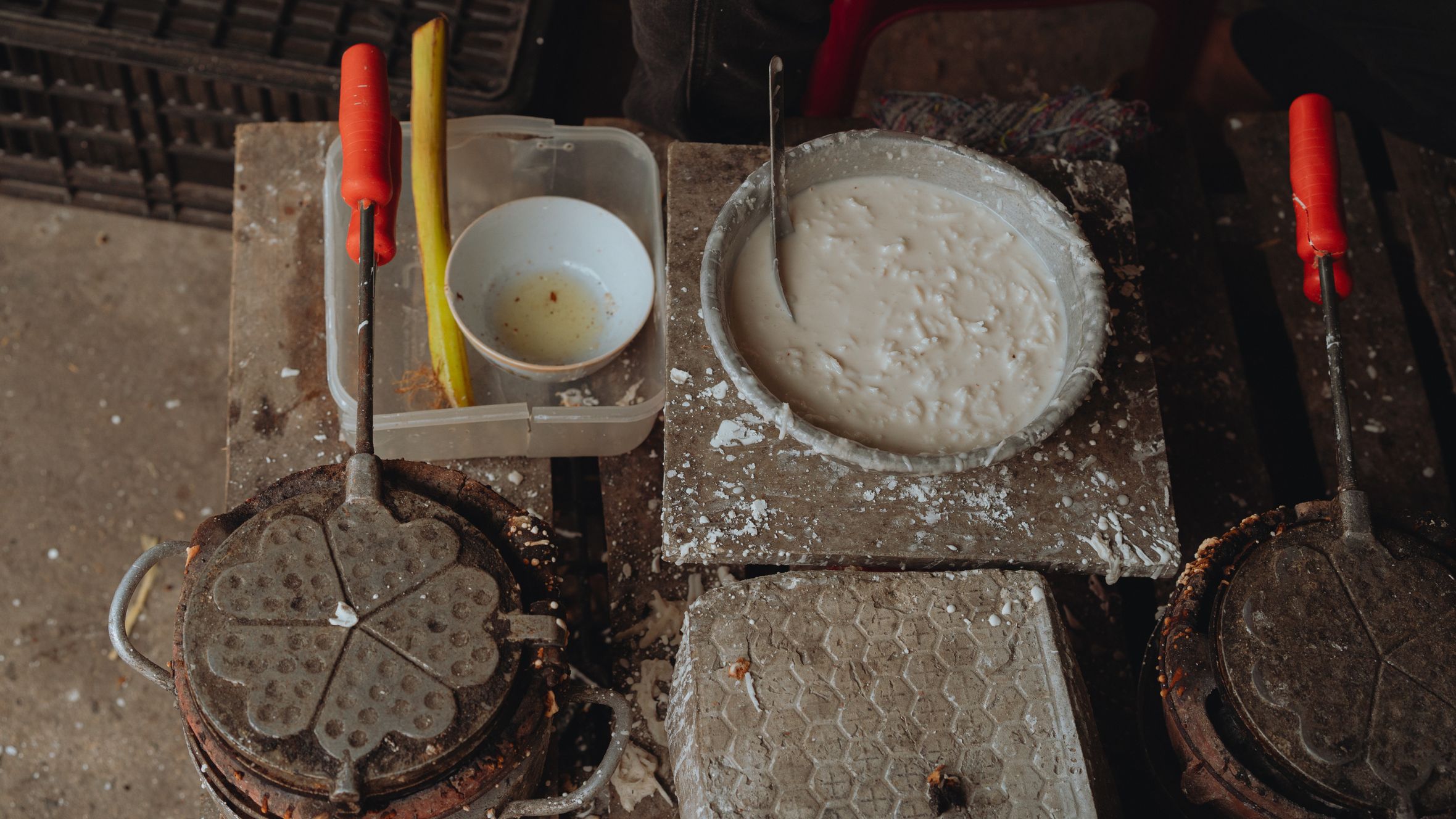 Authentic scene of Vietnamese waffle making with rustic tools and ingredients on display.