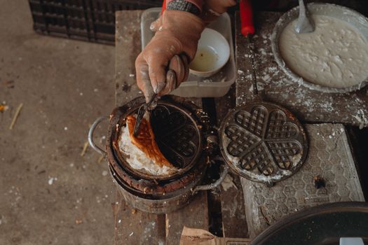 Close-up of a vintage waffle iron used in street food preparation in Bình Thuận, Vietnam.