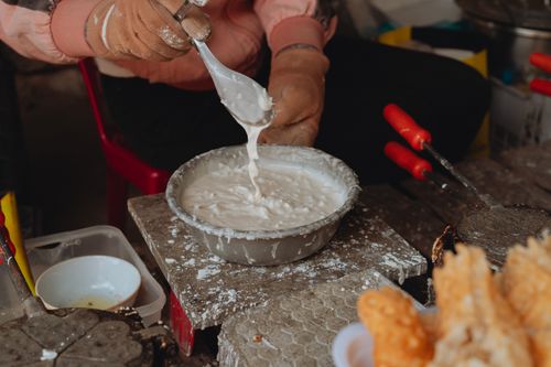 Free Close-up of a Vietnamese street vendor making traditional waffles with batter in Bình Thuận. Stock Photo