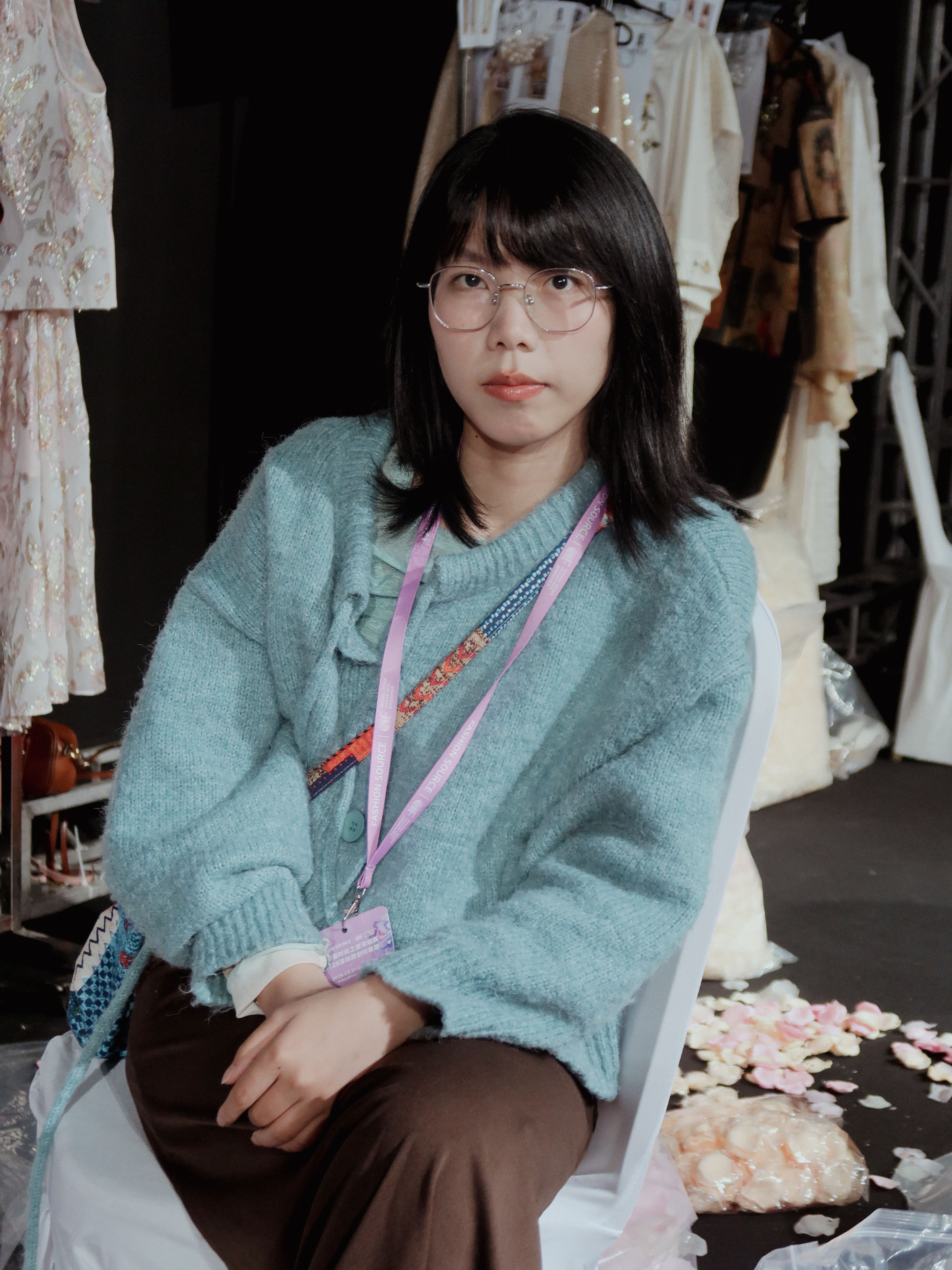 Candid backstage photo of a model at Shenzhen fashion show, capturing a relaxed moment.