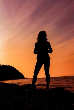 Silhouette of a person enjoying a vibrant sunset by the sea in Mudanya, Türkiye.