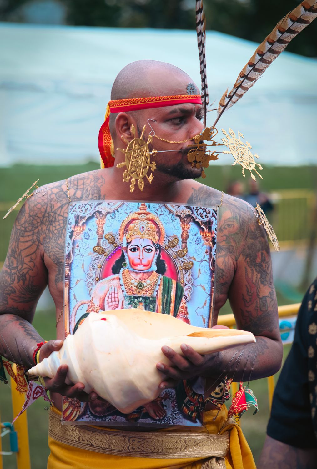 Tattooed Man in Ritual Attire Holding a Conch Shell · Free Stock Photo