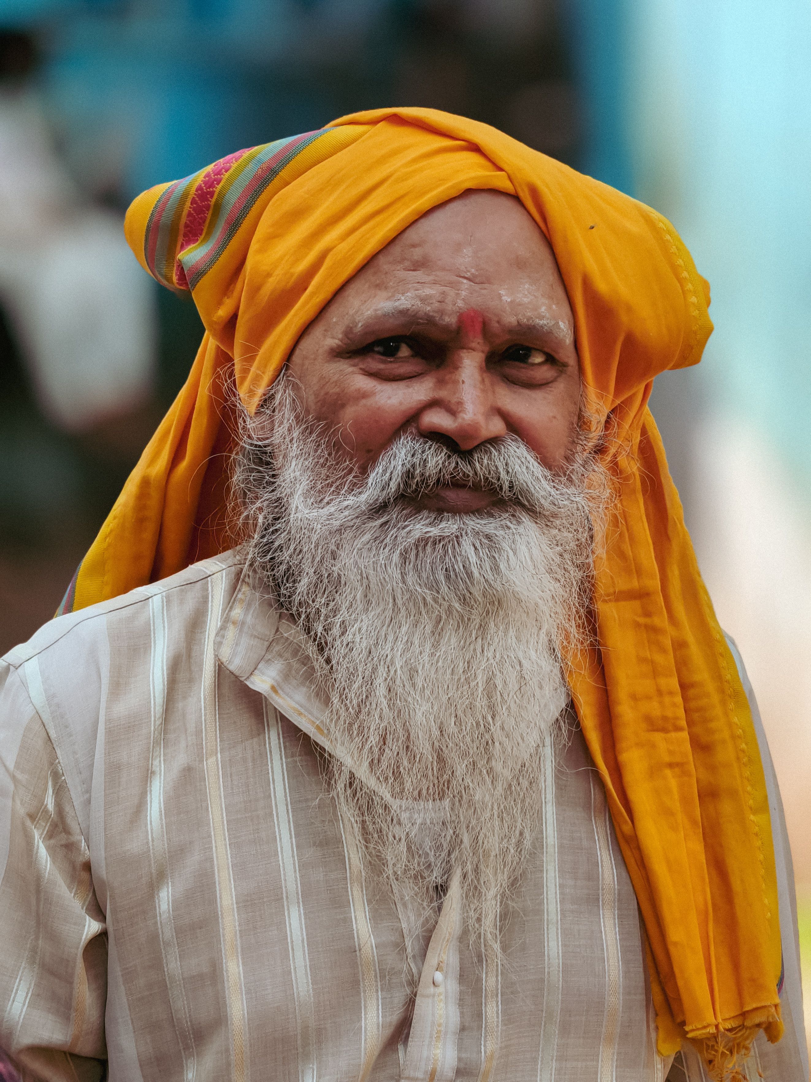 A traditional portrait of an elderly man wearing a colorful yellow turban in Varanasi, India, displaying cultural heritage.