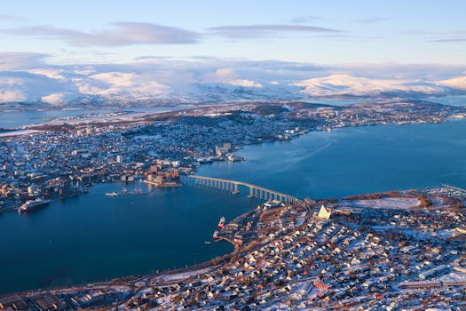 Panoramic aerial view of Tromsø, Norway, showcasing snow-capped mountains and the iconic Arctic Cathedral.