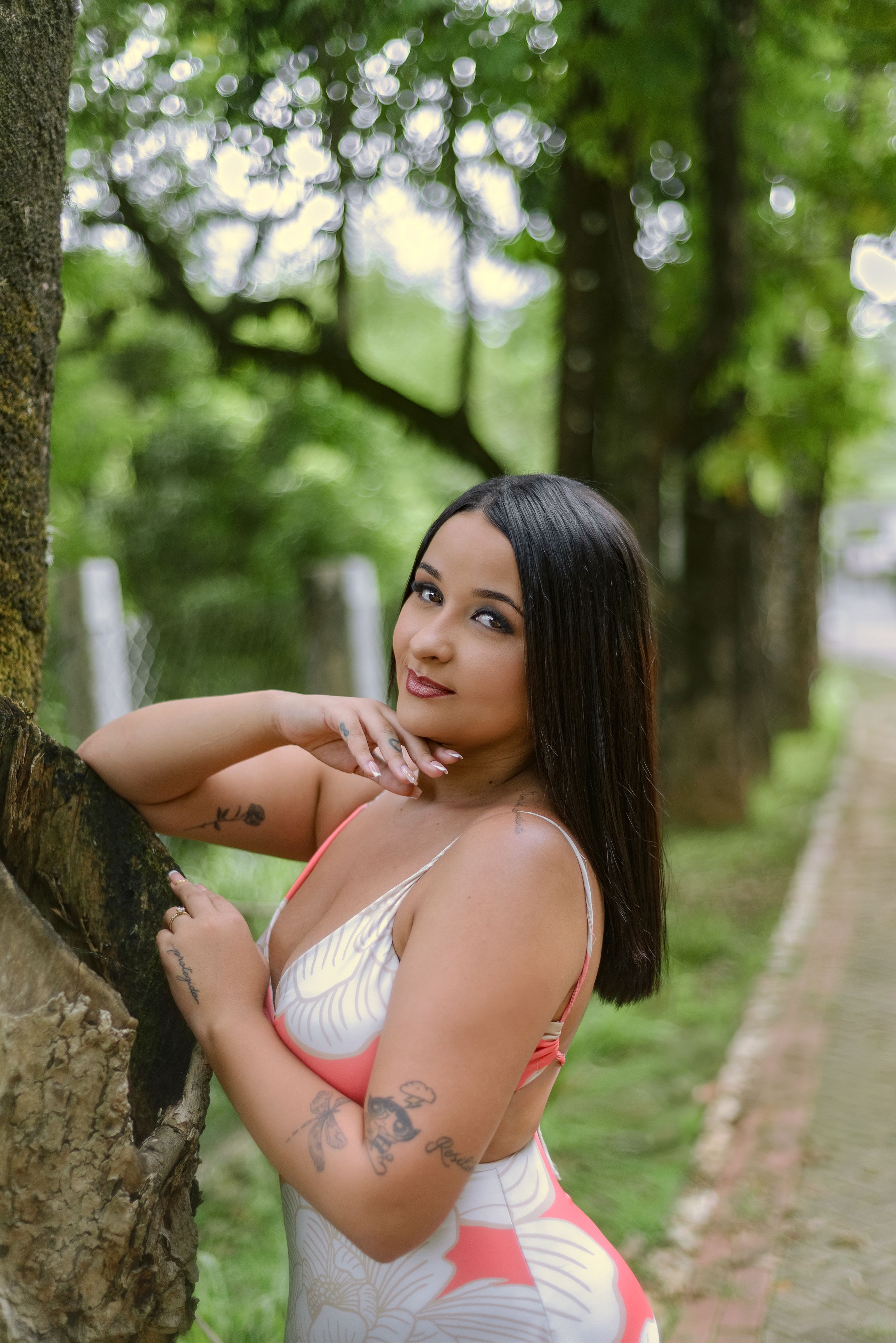 A serene portrait of a woman posing outdoors amidst lush greenery, reflecting elegance and tranquility.