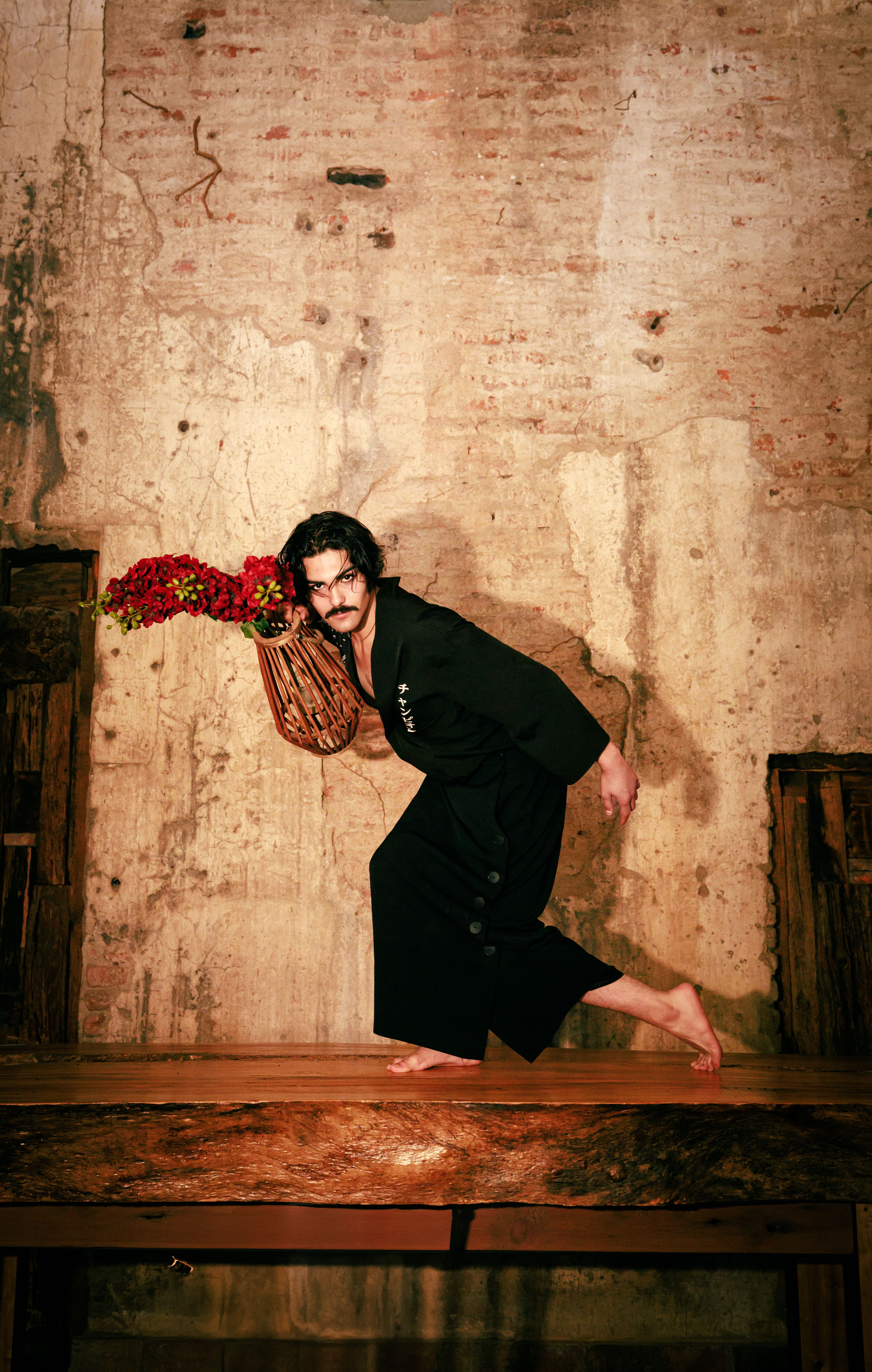 A male model striking a pose with flowers in an artistic setting. Captured in León, Mexico.