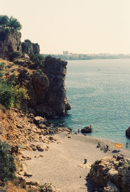 A beautiful rocky beach with clear blue waters in Antalya, Türkiye, perfect for summer relaxation.