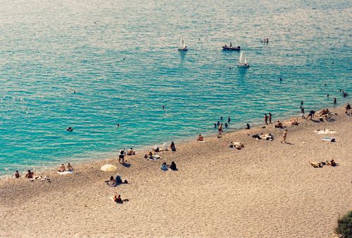 Free Aerial view of people relaxing on Antalya's sandy beach with sailboats in the turquoise sea. Stock Photo