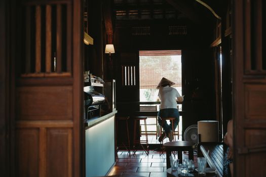A serene coffee shop interior featuring a lone patron enjoying a quiet moment by the window.