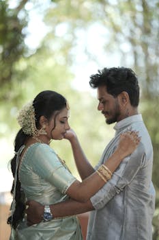 A couple shares a tender moment with natural light filtering through the greenery, creating a dreamy atmosphere.