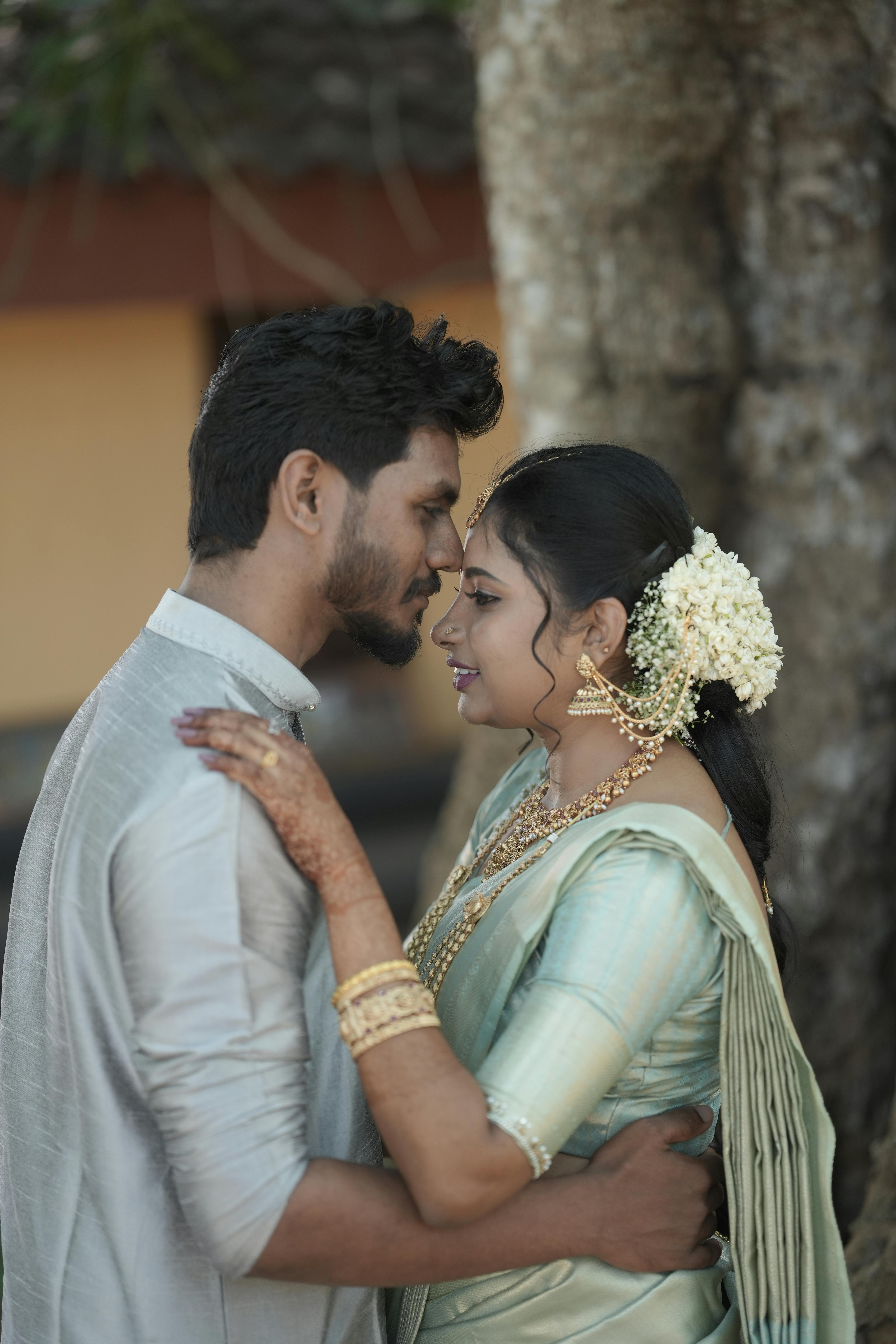 A couple sharing an intimate moment outdoors in traditional clothing under natural light.