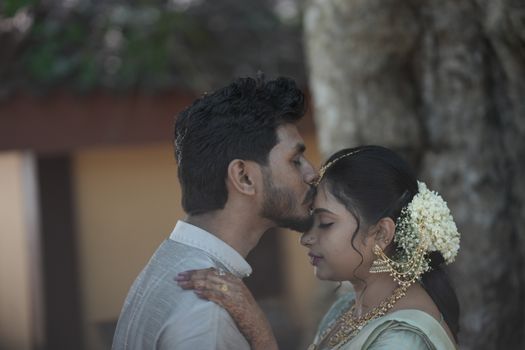 A couple sharing a tender moment under natural light, captured outdoors with serene, earthy tones.