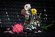 在闪闪发光的背景下，一双时尚的黑色靴子装饰着花卉图案和五颜六色的花朵