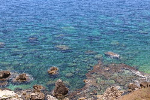 Free Stunning view of vivid blue ocean and rocky shoreline under clear skies. Stock Photo