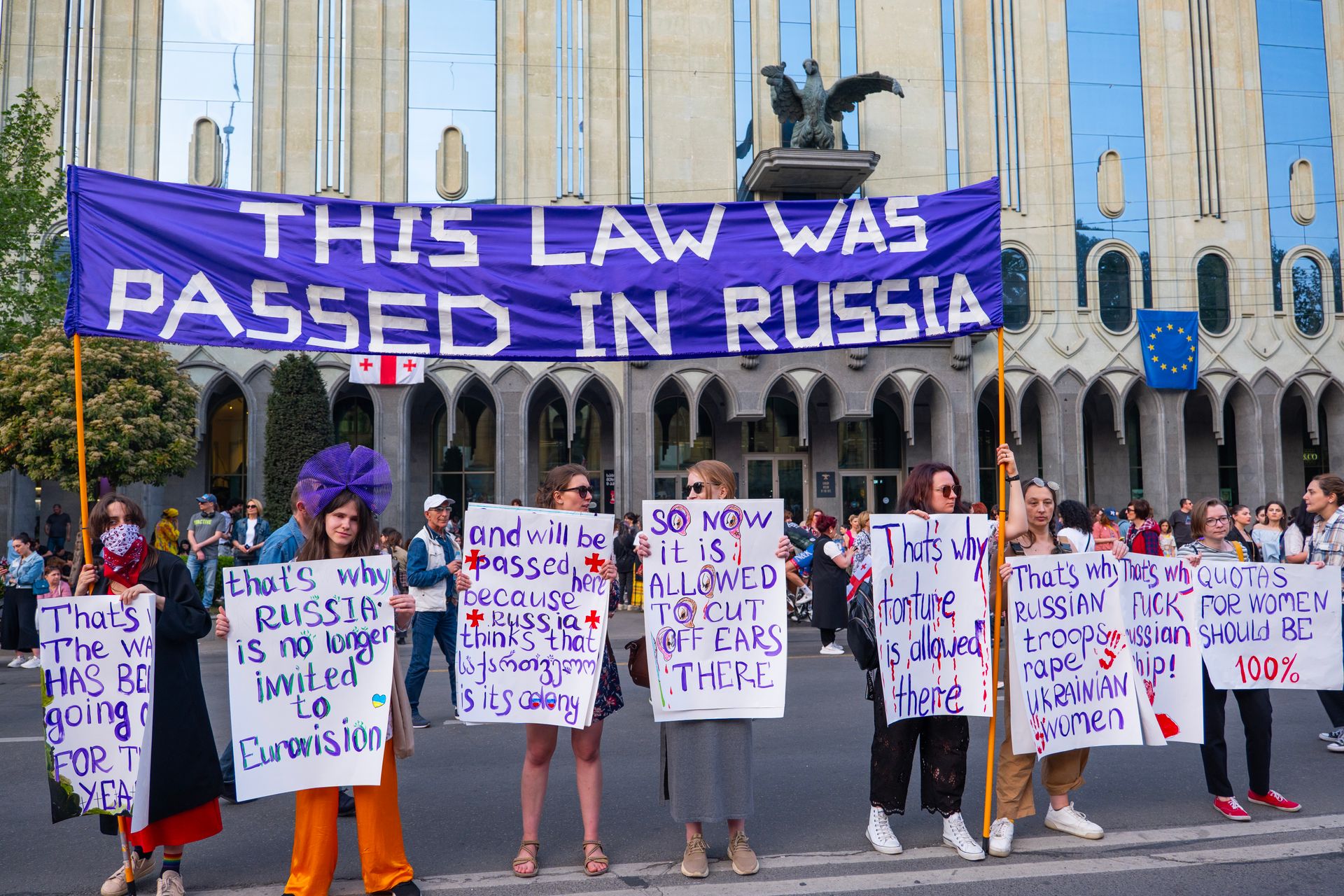 Protestors in Tbilisi rally against Russian laws, holding signs for freedom and independence.