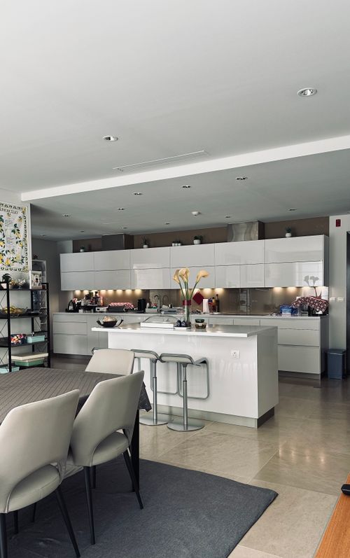 Free Sleek modern kitchen featuring white cabinets, island, and elegant decor. Stock Photo