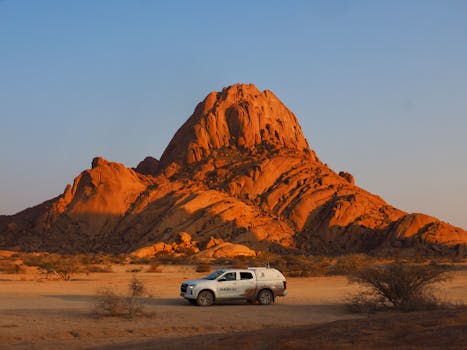 Dramatic sunset over Spitzkoppe, Namibia with a car in the foreground.