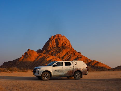 4x4 vehicle exploring the iconic Spitzkoppe mountain, Namibia at sunset, showcasing adventure travel.