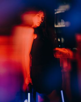 Artistic image of a woman shrouded in blurred colorful neon lights, creating a moody and vibrant effect.