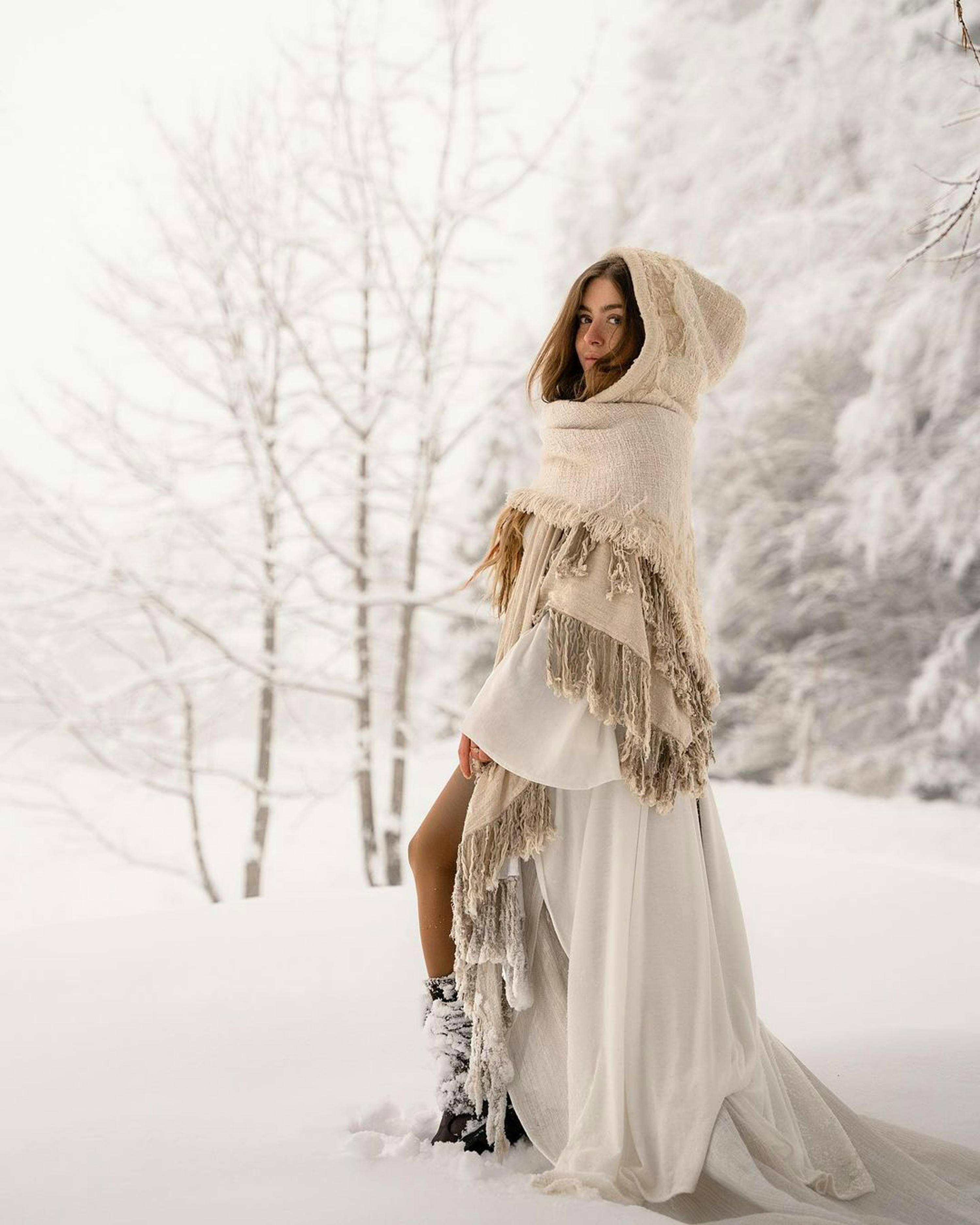 Elegant woman in winter fashion standing in a snowy forest landscape.