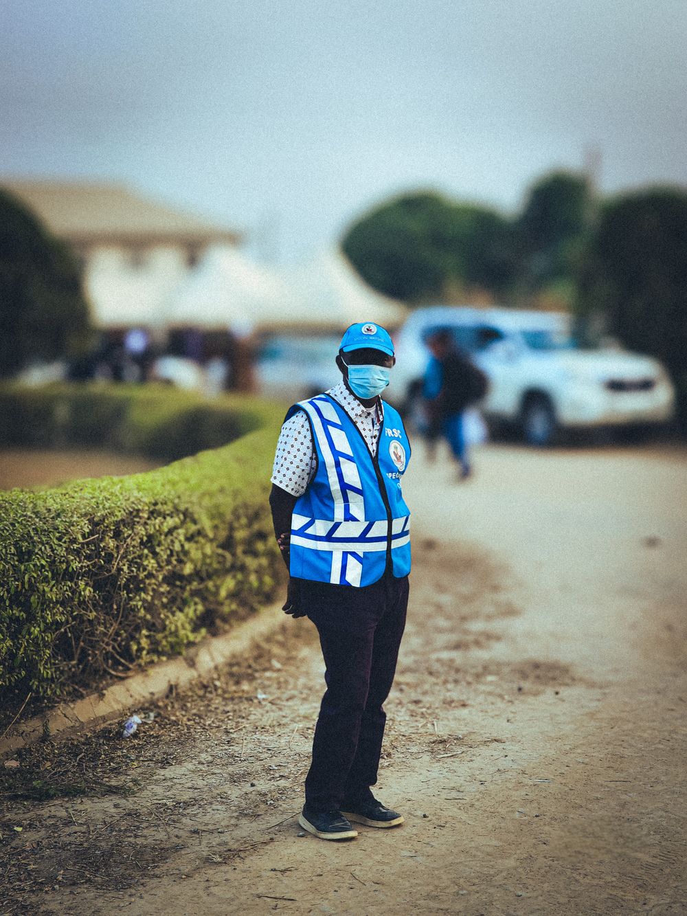 Security guard in a blue vest and cap standing outdoors