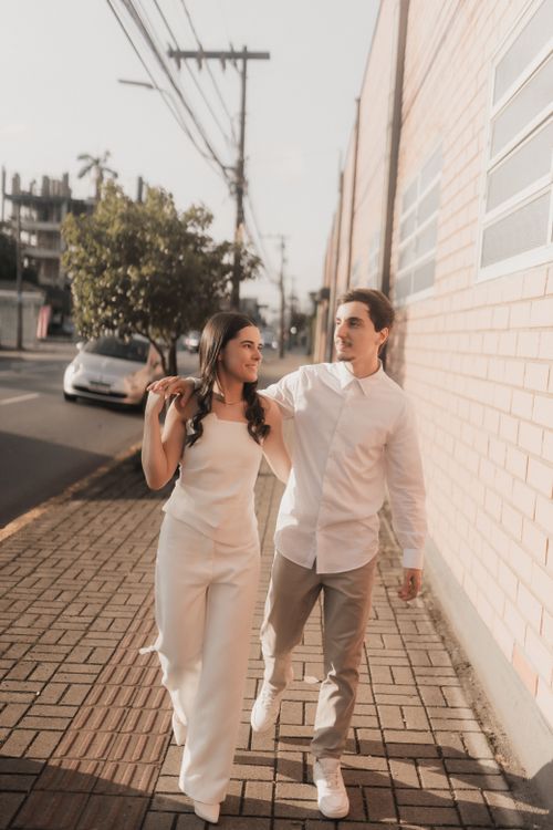 Free Young couple strolling arm in arm on an urban street during a sunny day. Stock Photo