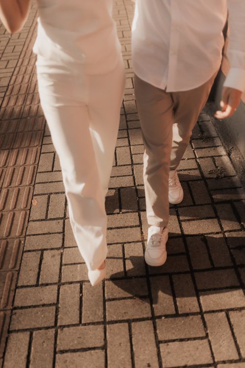 Free Stylish couple walking on a paved path under sunlight, highlighting their casual elegance. Stock Photo