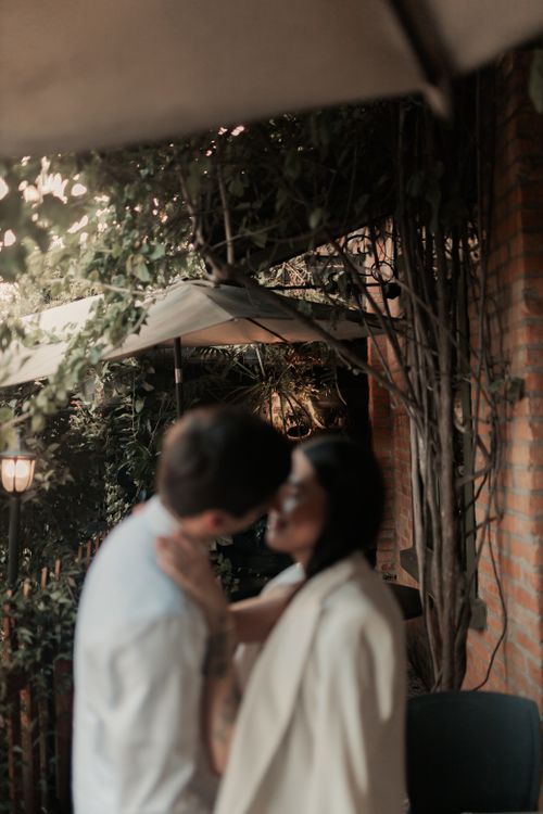 Free A blurred romantic scene of a couple sharing a kiss in an outdoor garden setting. Stock Photo