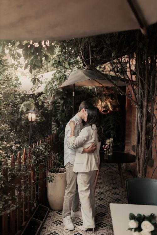 Free A couple shares a warm embrace in a charming outdoor garden setting. Stock Photo