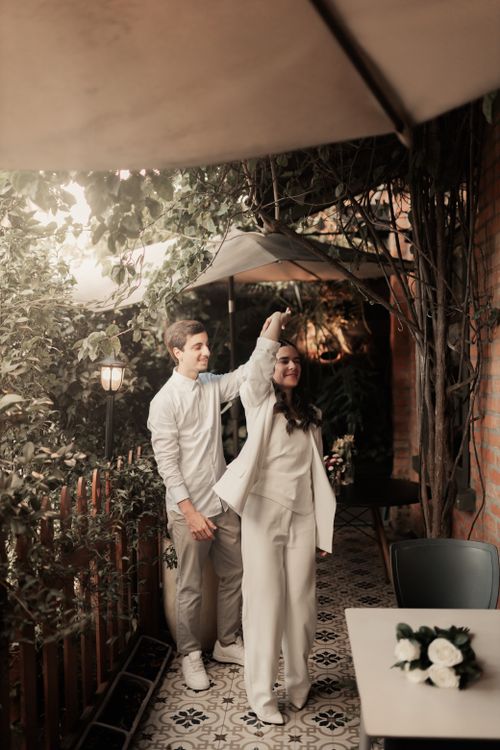 Free A couple gracefully dancing in an intimate, plant-filled outdoor café setting. Stock Photo