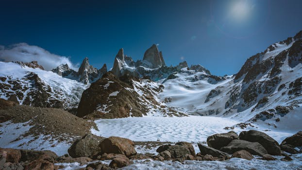 Majestic snow-covered mountains and rugged terrain in El Chaltén, Argentina under a clear winter sky.