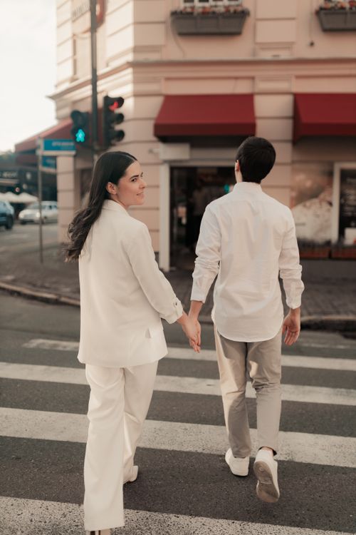 Free Romantic couple walking hand-in-hand across a city street. Stock Photo