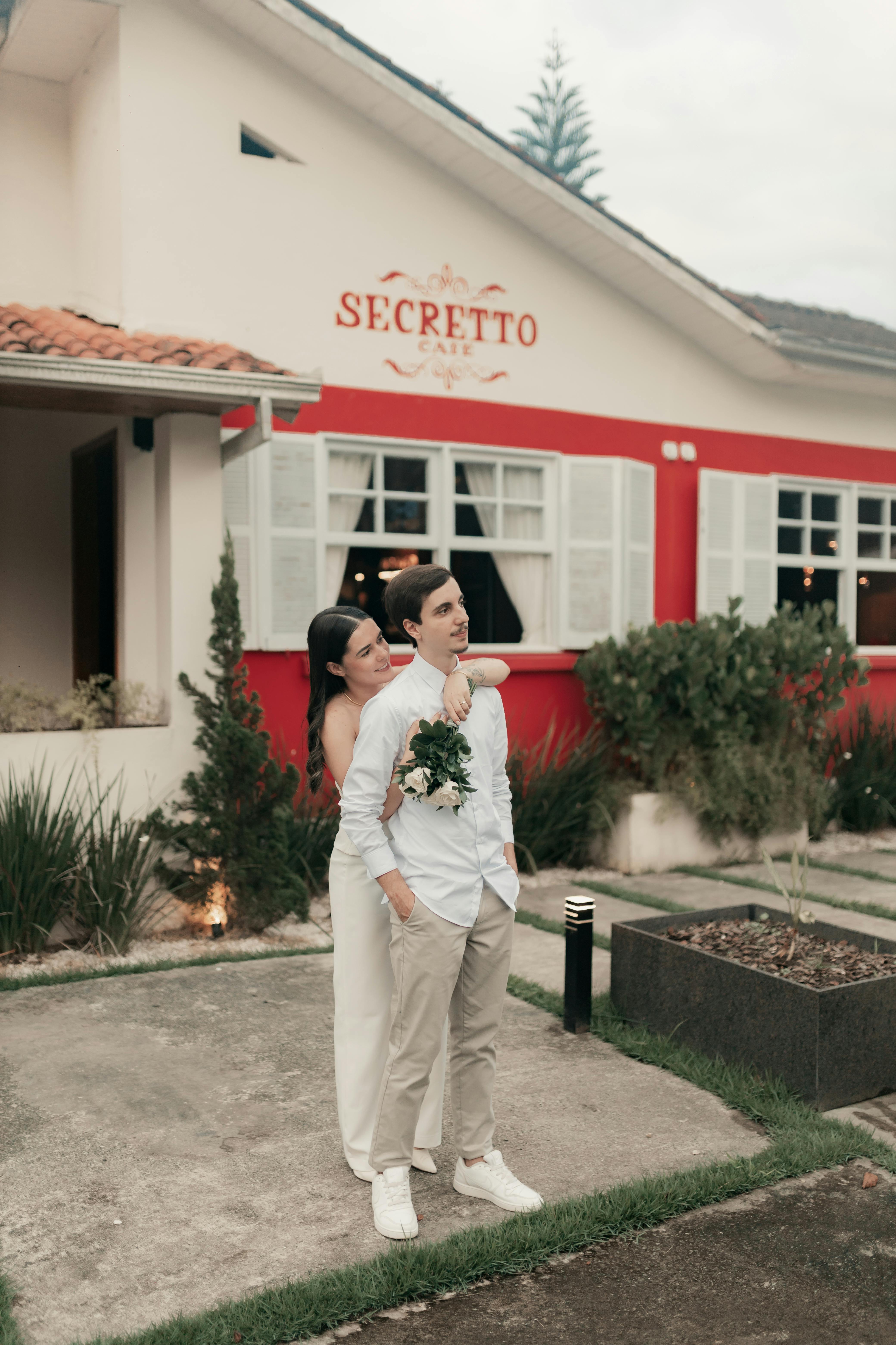 A couple embraces in front of Secreto Café, evoking romance and joy.