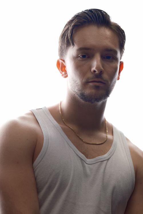 Free Close-up portrait of a man in a white tank top with a necklace, backlit lighting. Stock Photo