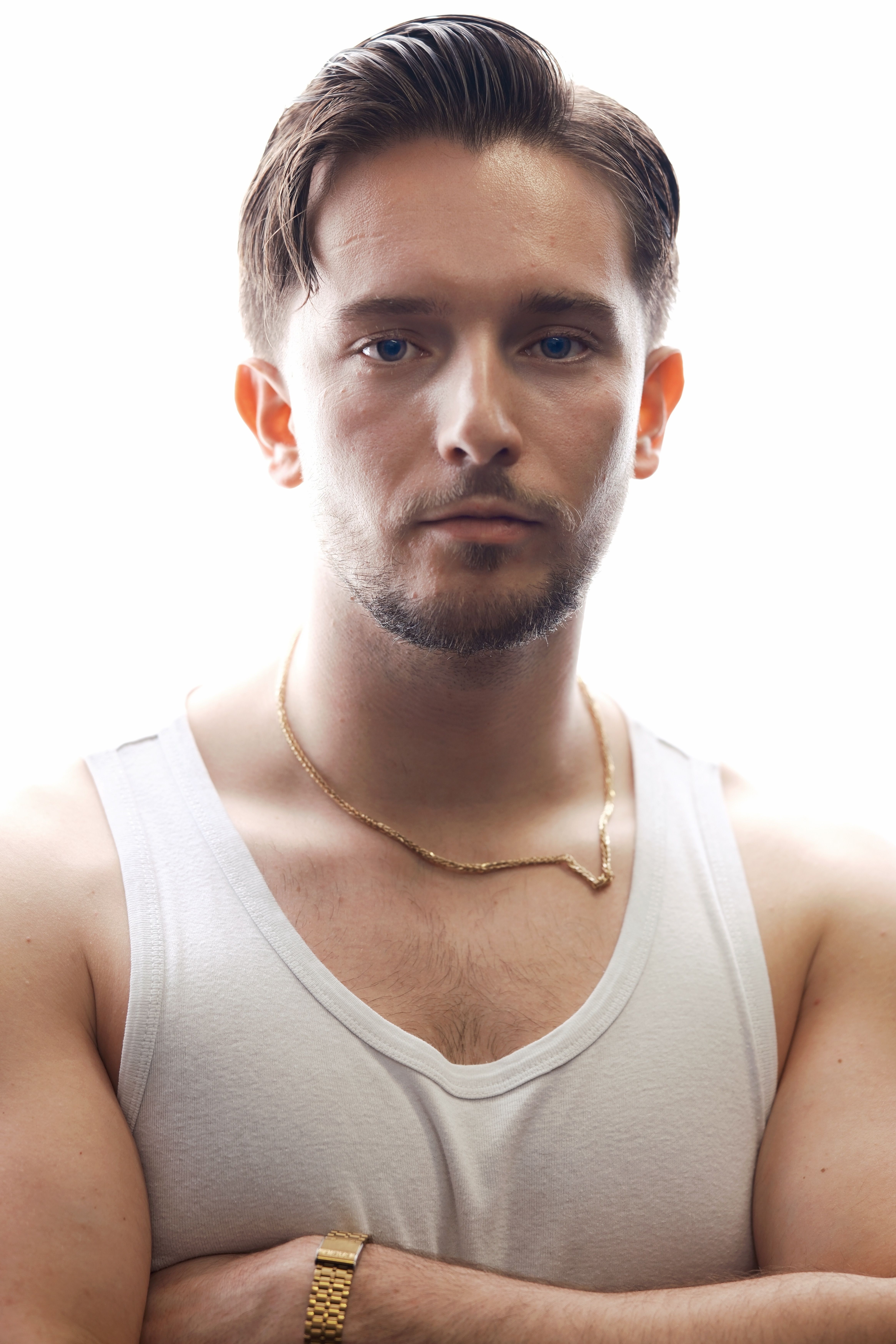 Portrait of a young man in a white tank top against a white background, exuding confidence.