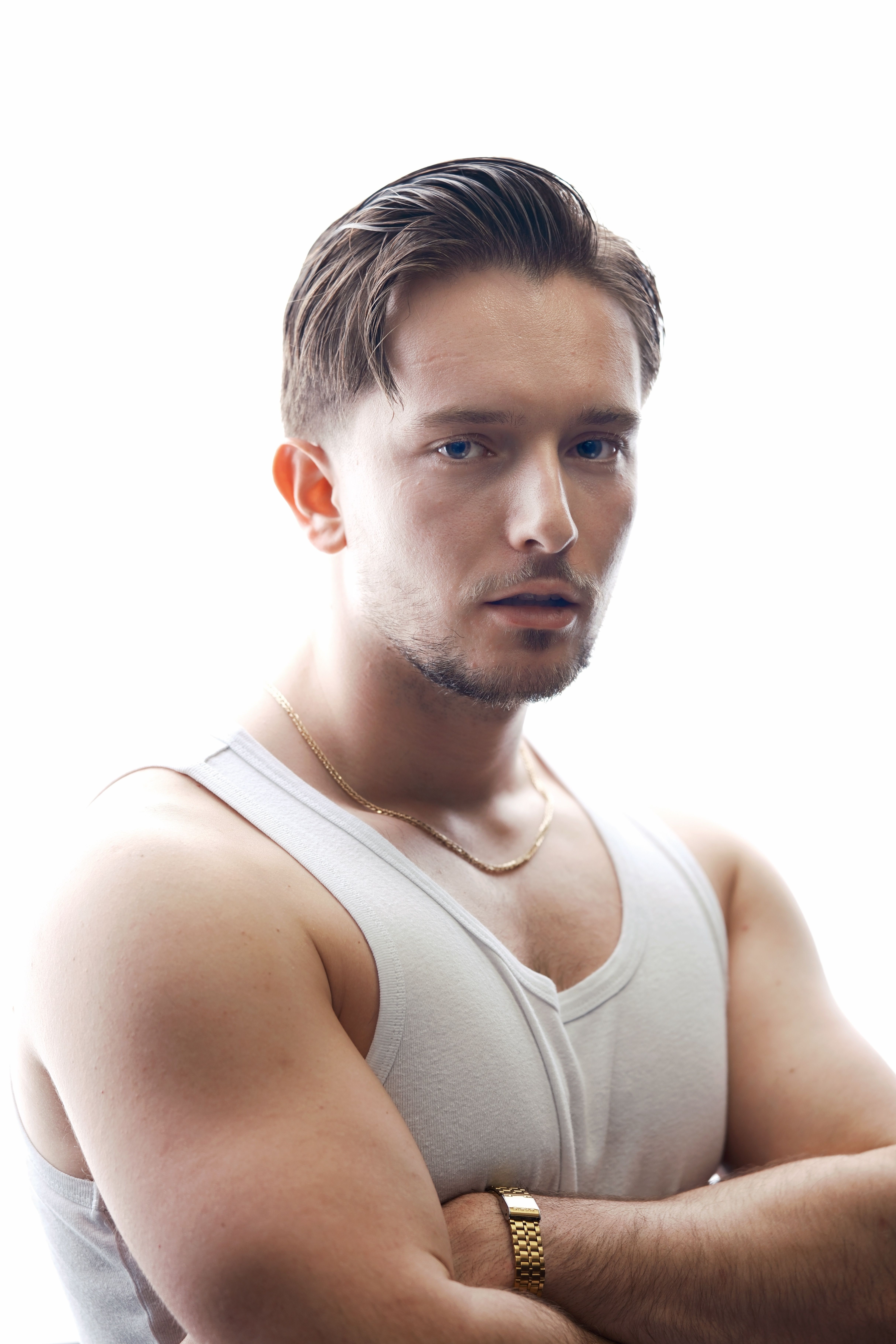 Portrait of a confident young man in a white tank top with a neutral background.