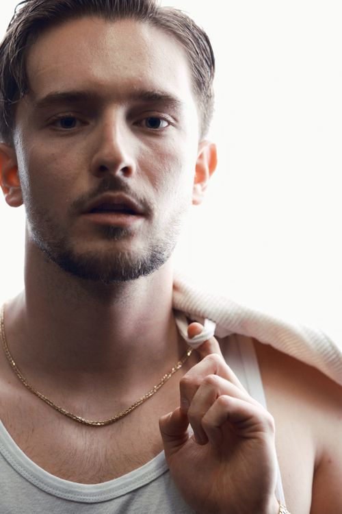 Free Close-up portrait of a young man with a chain necklace in a casual pose, exuding modern style. Stock Photo