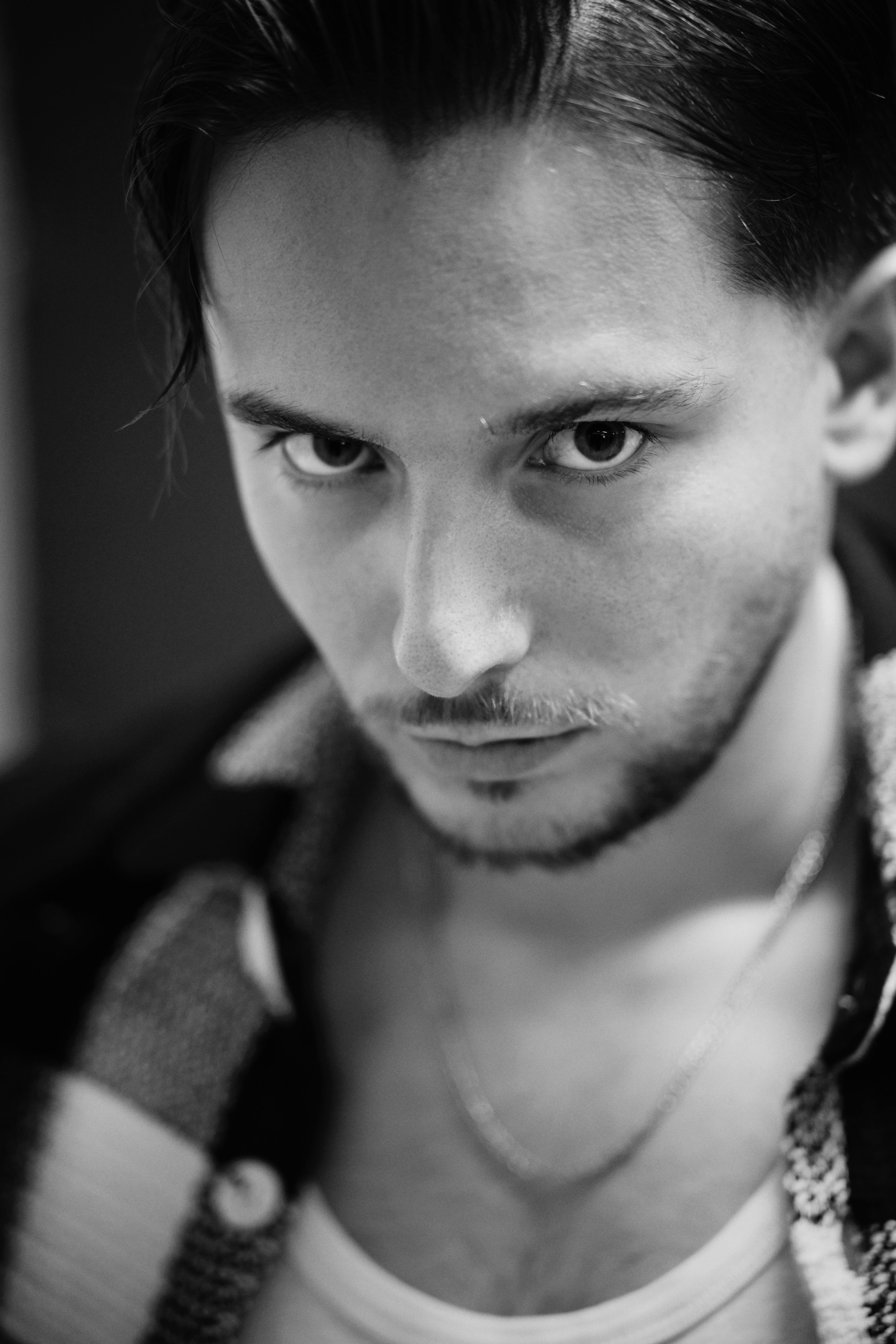 Dramatic close-up black and white portrait of a man with intense gaze.