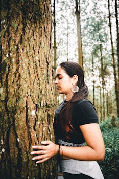 Young woman embracing a tree in a serene pine forest setting, promoting natural harmony.