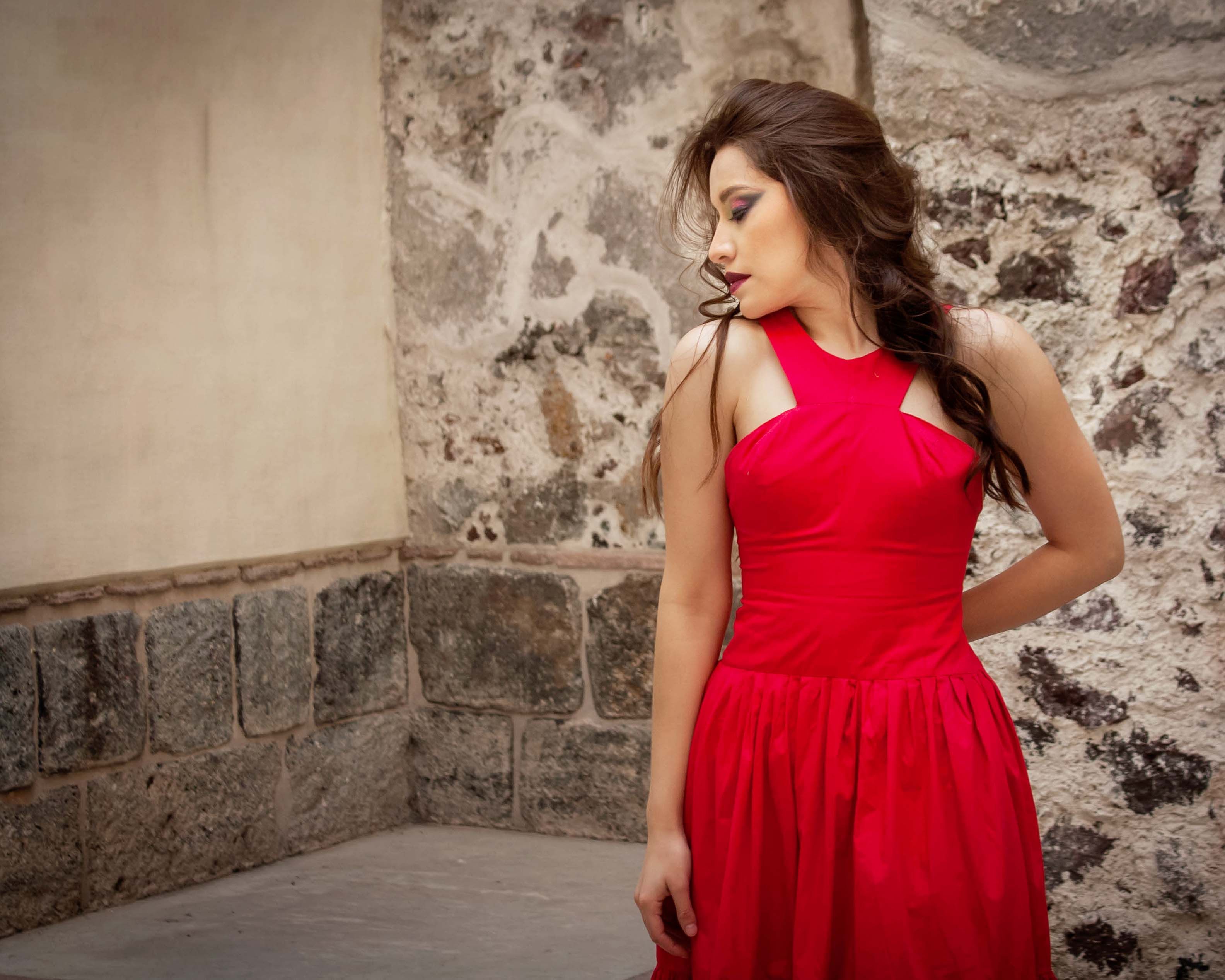 Elegant Woman in Red Dress Leaning on Stone Wall · Free Stock Photo