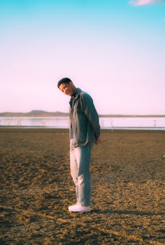 Young man standing by a lake in Ouargla, Algeria during sunset, creating a serene and contemplative mood.