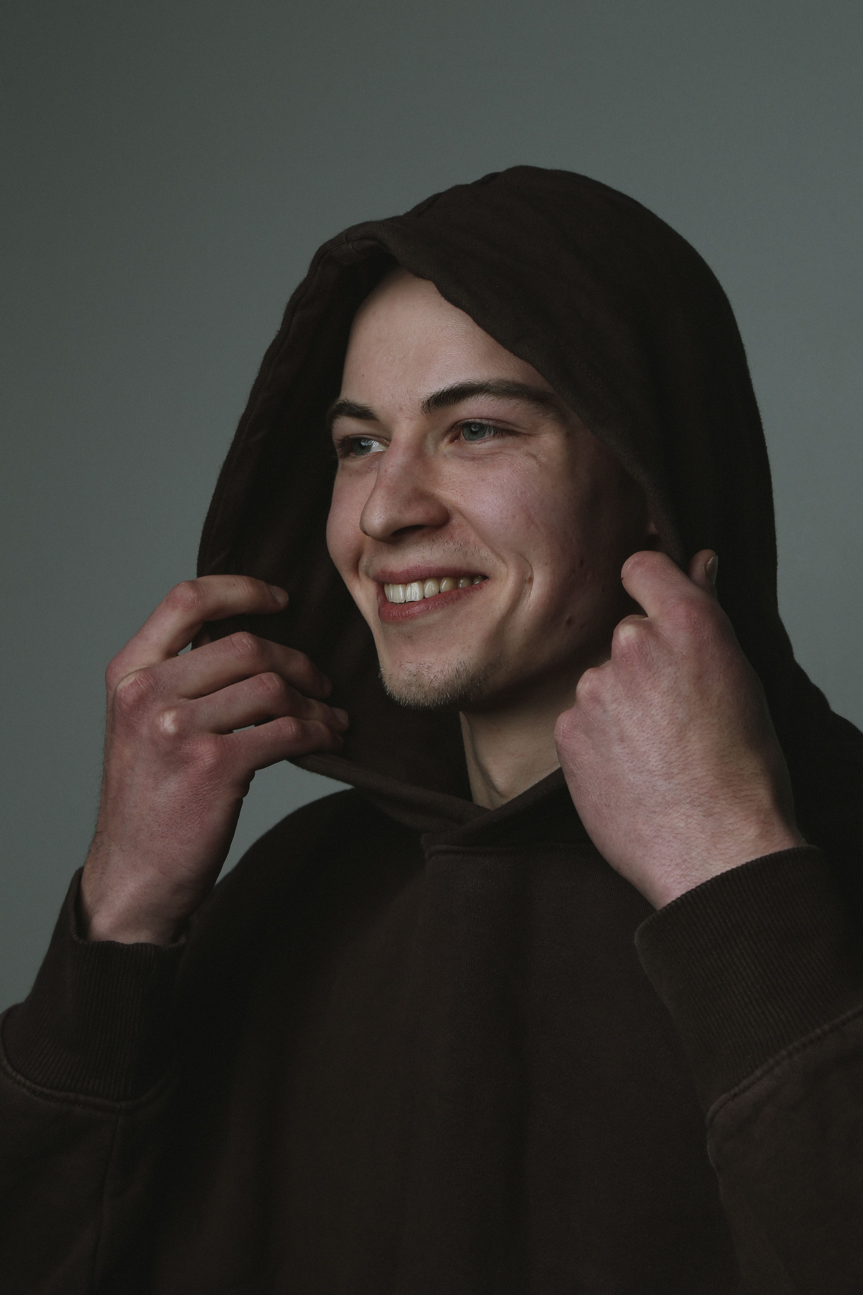 Portrait of a smiling man wearing a hoodie, captured indoors in Berlin.
