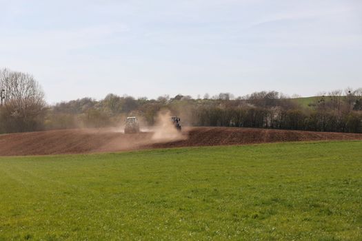 A tractor plowing a field under a clear blue sky, signifying spring agriculture.