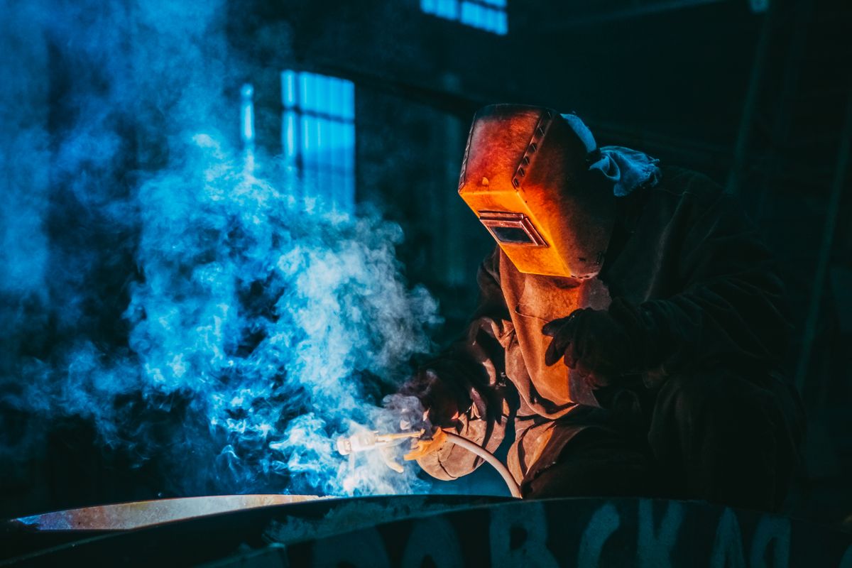 Worker in a workshop using safety gear to weld metal