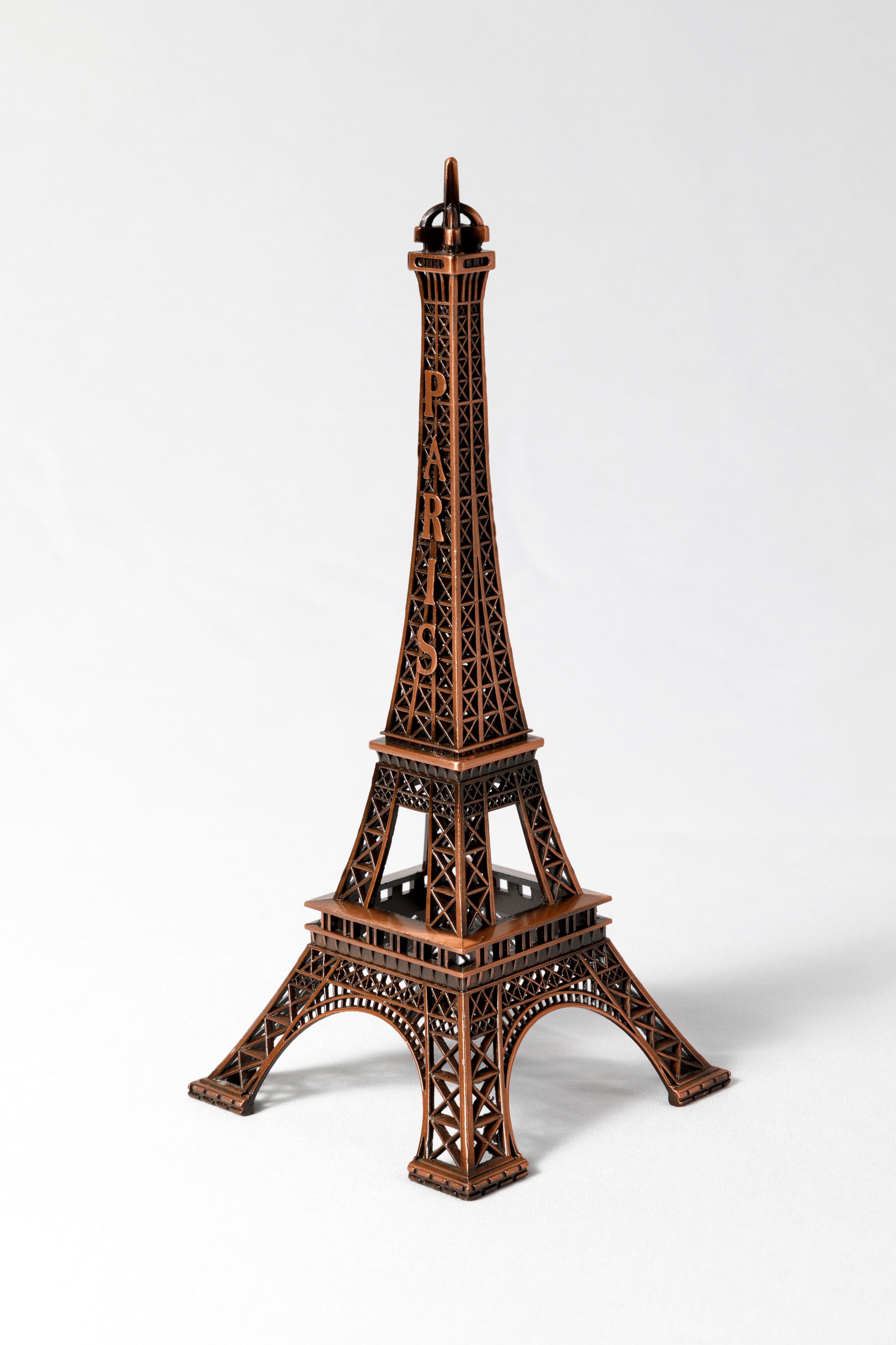 Close-up of a miniature Eiffel Tower model with Paris inscription on a white background.