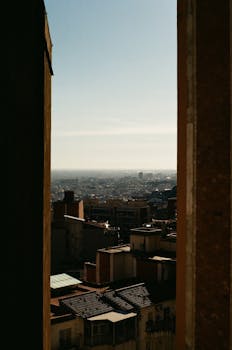 A stunning analog photograph capturing Barcelona's cityscape framed between buildings, showcasing urban life.
