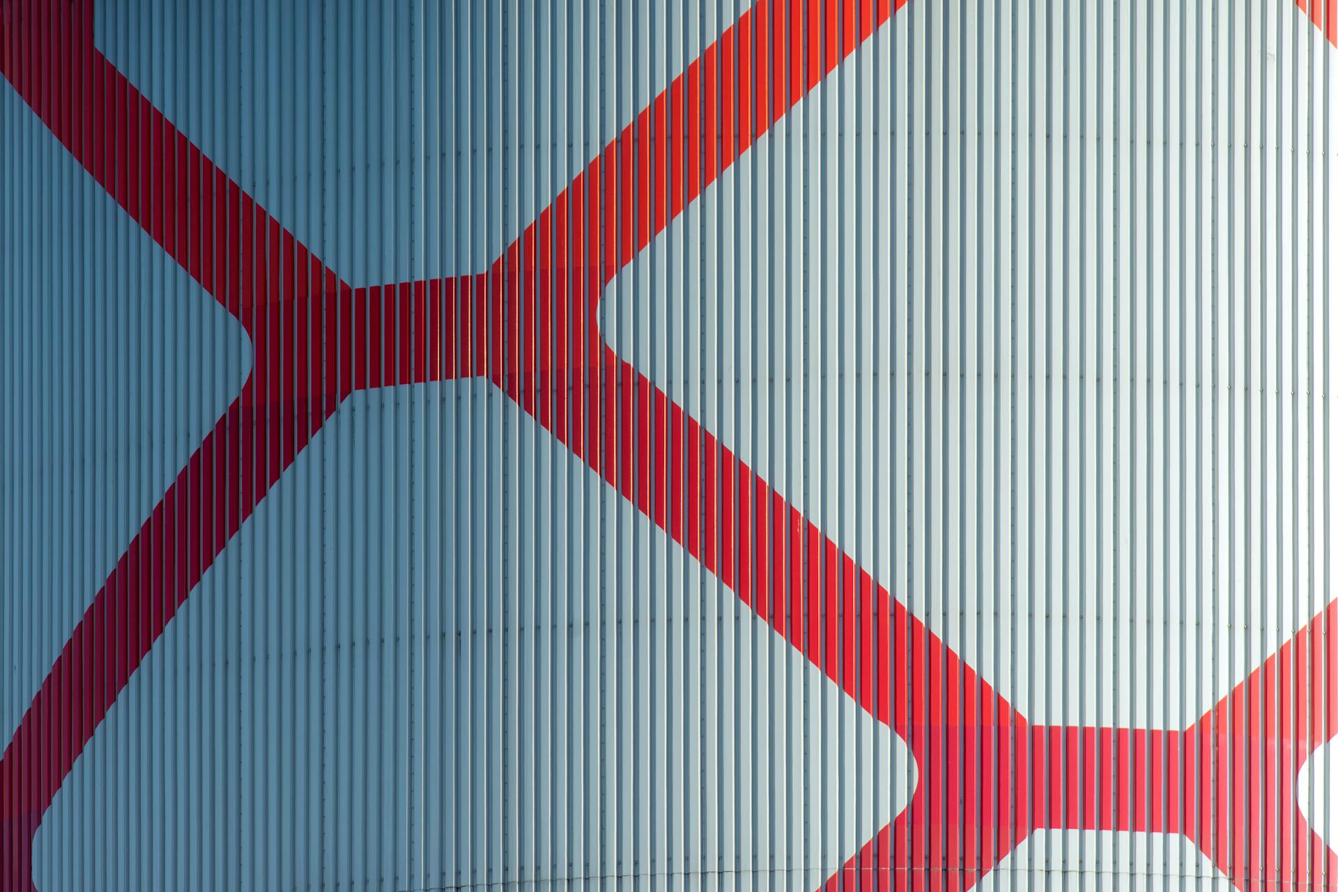 Close-up of a red geometric pattern on a blue corrugated industrial surface.